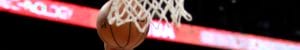 Hand on basketball thrown behind basketball net