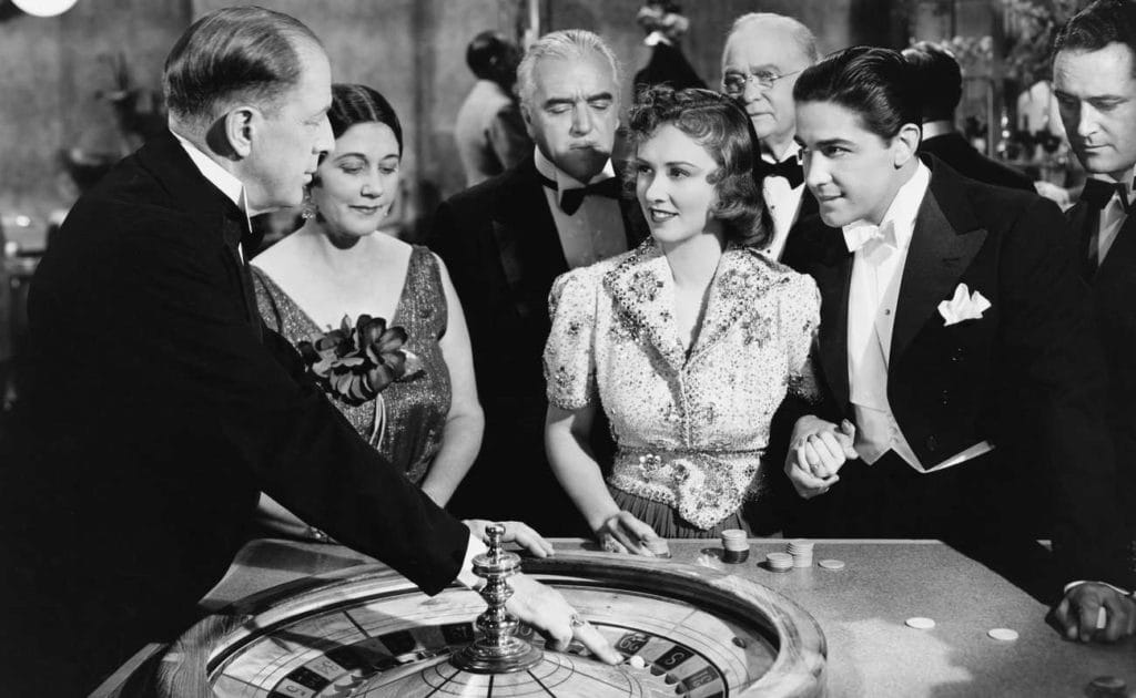 black and white photo of vintage casino with people at roulette table 