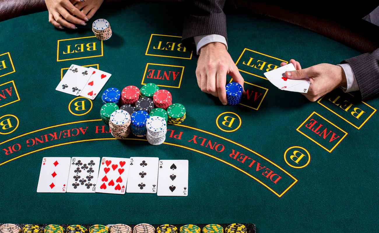 Couple playing casino card games on a green table, with stacks of poker chips and cards laid out.