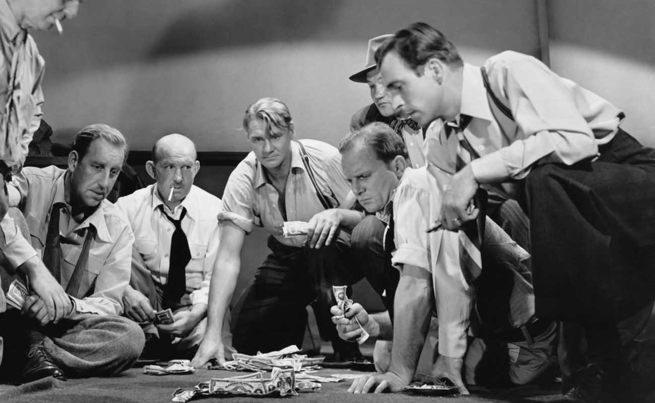 black and white photograph of worker men gambling on the floor