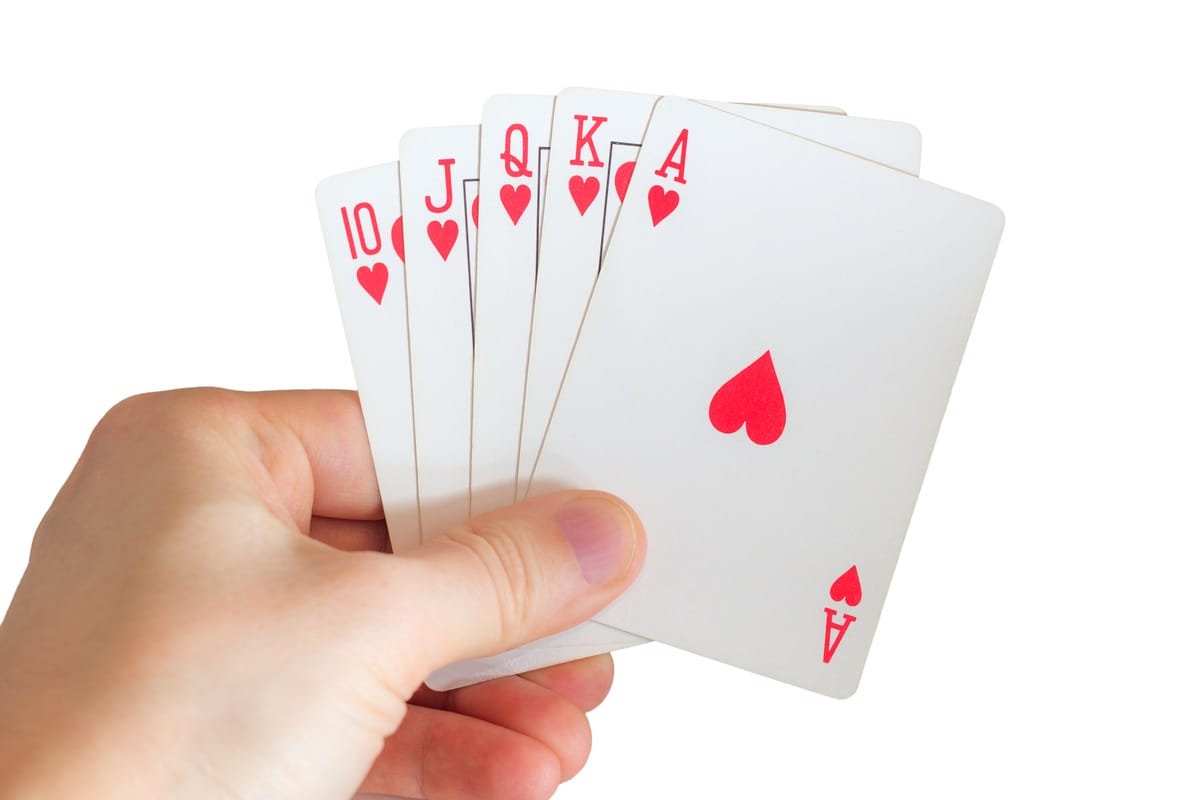 Male hand holding a red 10, Jack, Queen, King and Ace of Hearts cards