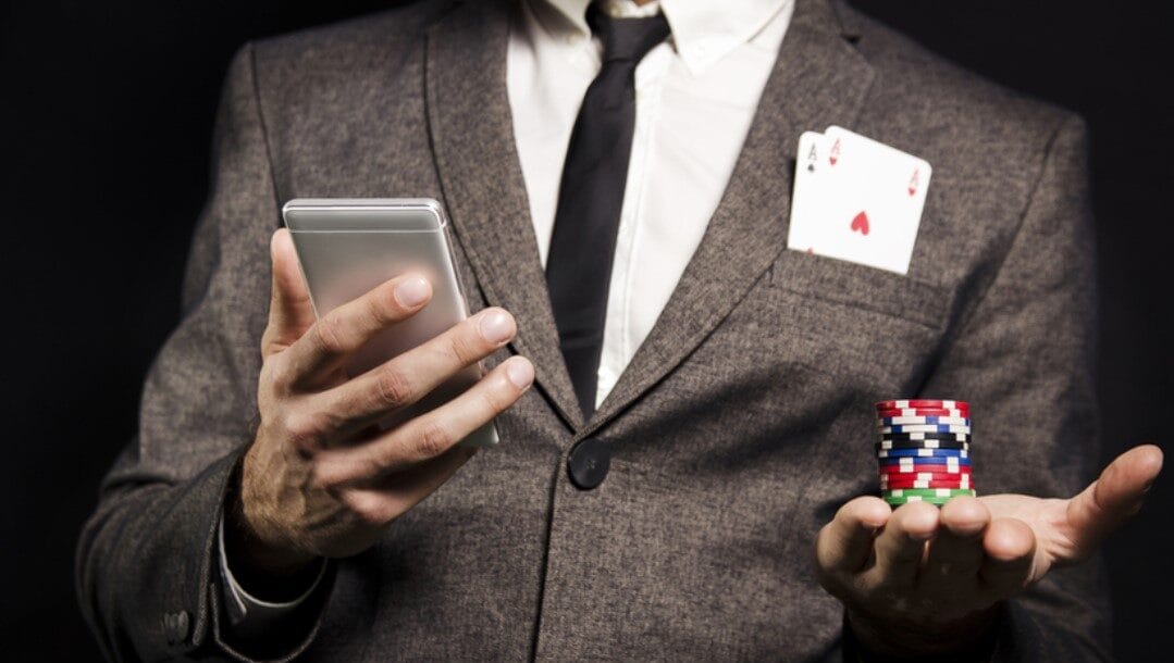 A man in a gray suit balances a stack of casino chips in the palm.