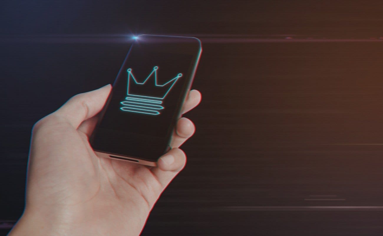 Close up of man hand holding a smartphone with Crown Icon