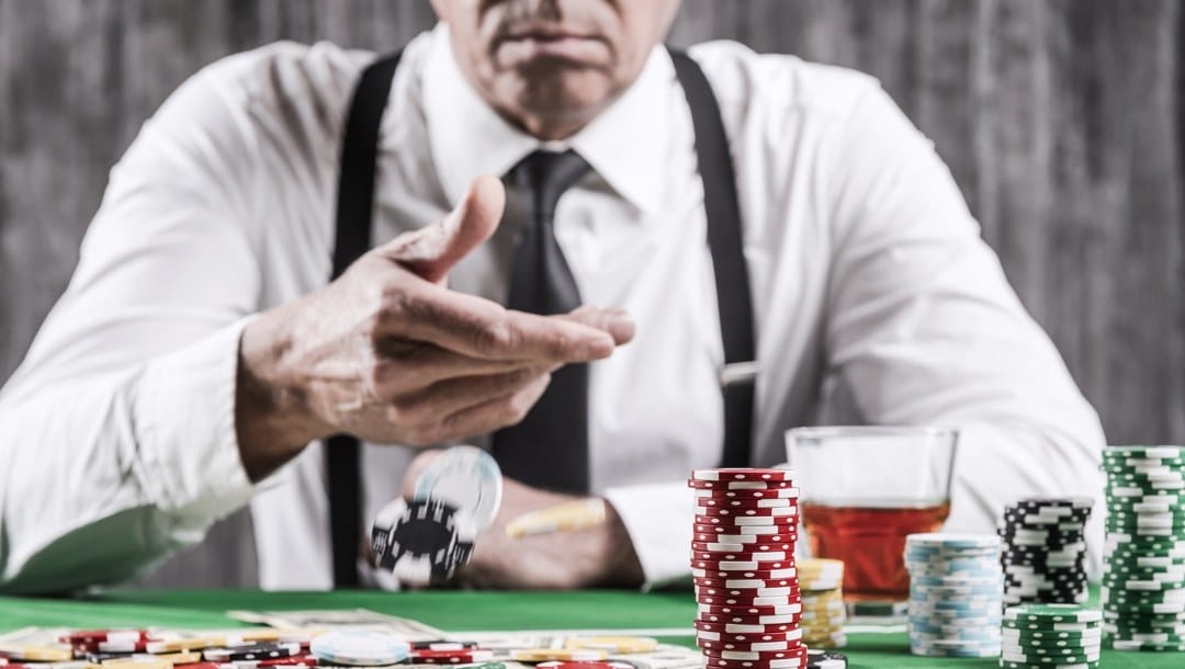 A man tosses his chips onto a poker table