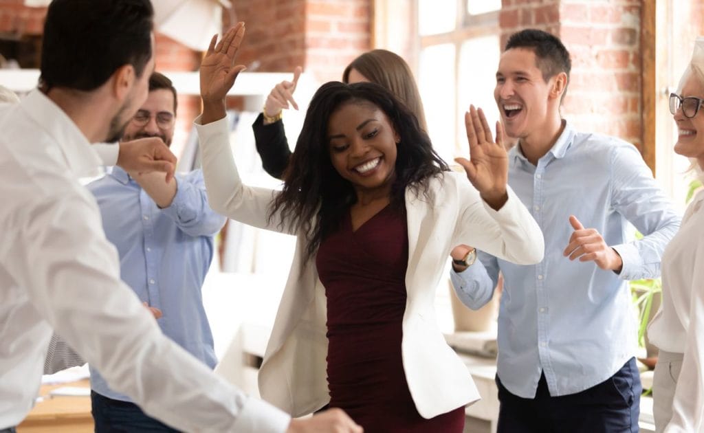 Happy businesswoman with coworkers enjoying victory dance