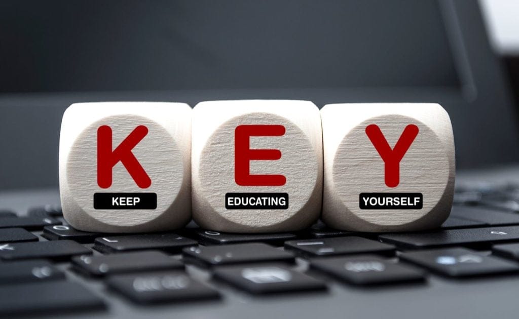 Cubes dice on keyboard with the words KEY Keep Educating Yourself