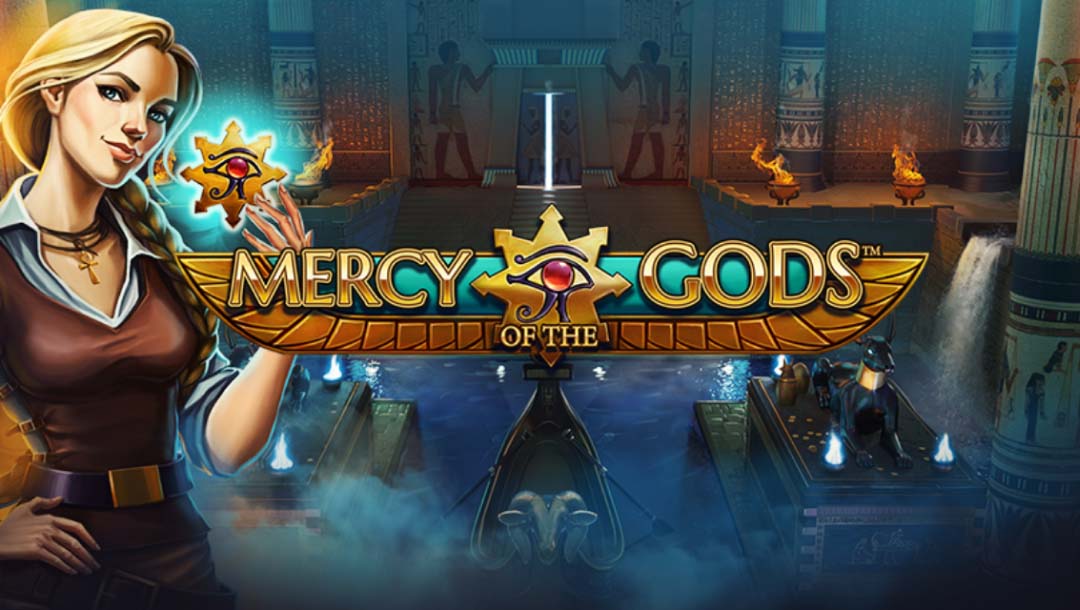 Mercy of the Gods Touch online slot loading screen with a woman holding the eye of Horus alongside the logo which is in gold, turquoise, and black. The background shows the inside of an Egyptian tomb with several Egyptian artefacts.