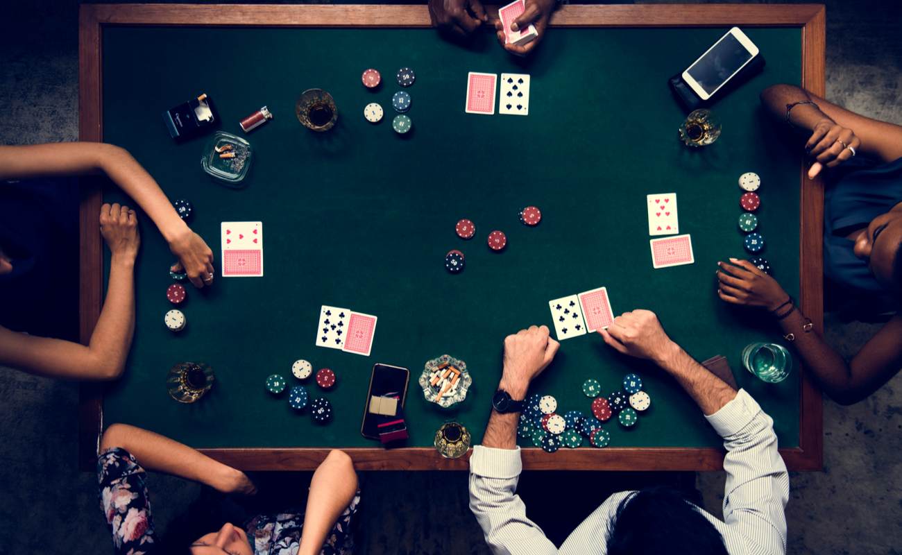 Aerial view of people at a poker table with cards and poker chips