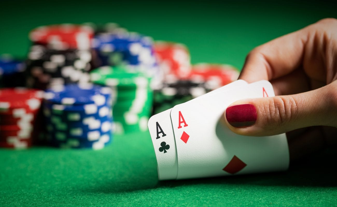 Hand holding two ace cards on poker table with poker chips