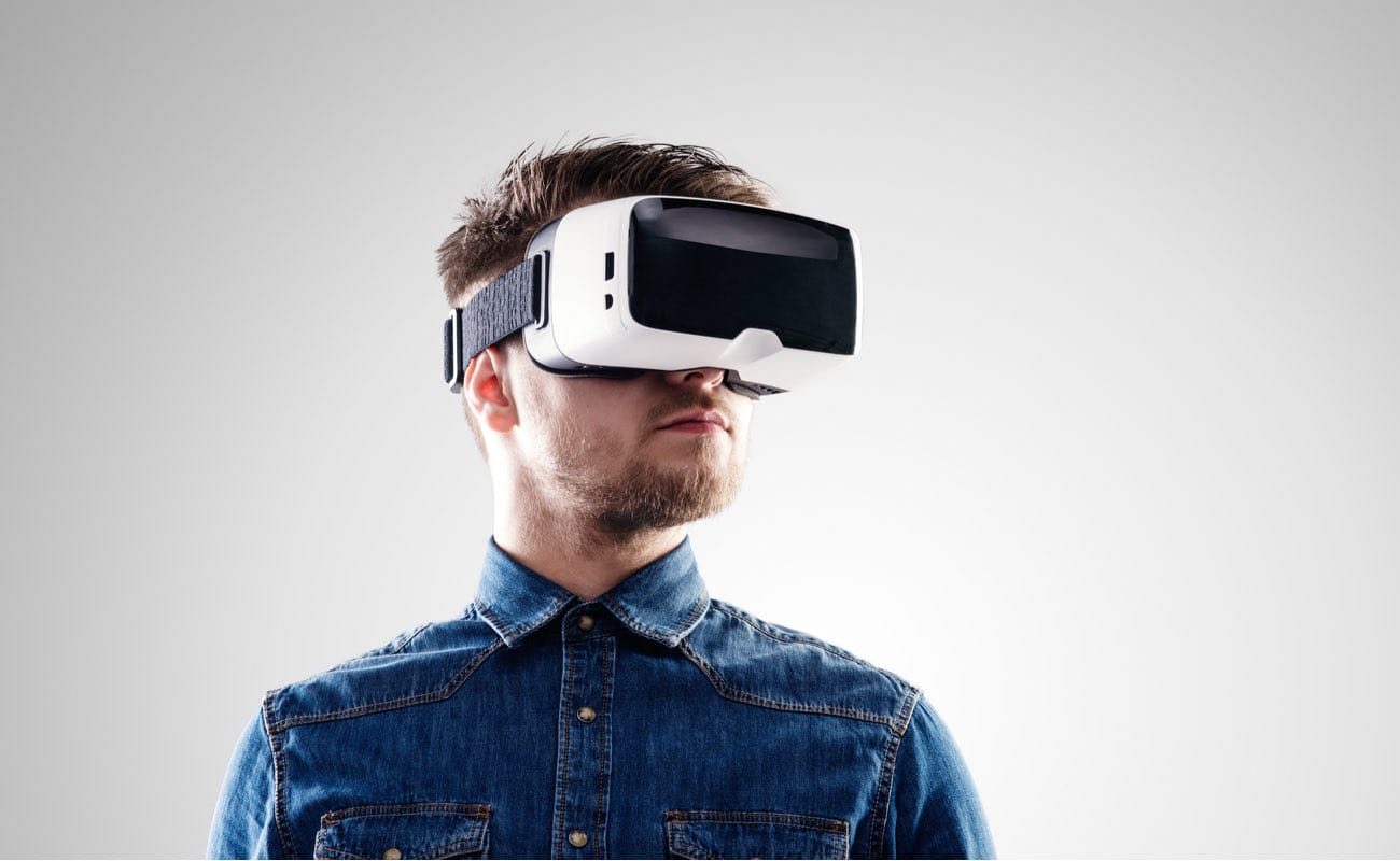 Man wearing virtual reality goggles shot in studio against grey background