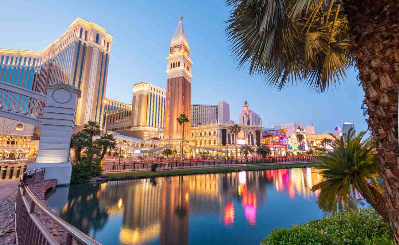 The Las Vegas Strip lit up in the evening and reflecting onto a water feature.