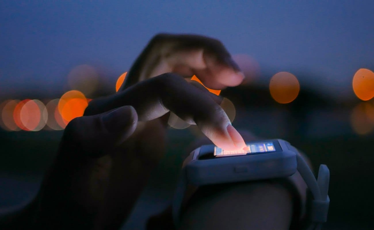 A Person Uses A Smartwatch with a Dark Background and Orange Lights