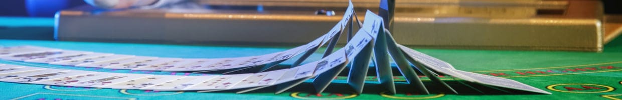 Professional croupier shuffling cards on a green felt casino table.