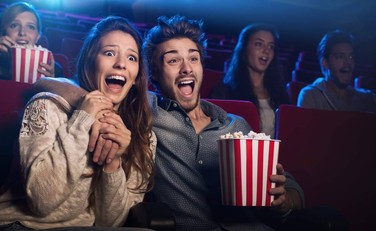 A young couple watch an exciting movie at the cinema.