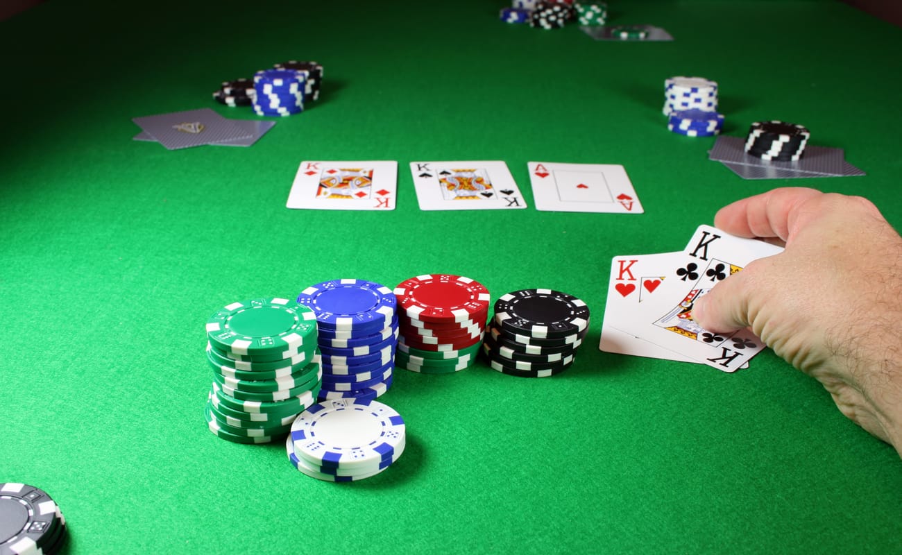 A player shows two kings next to some chips on a poker table.