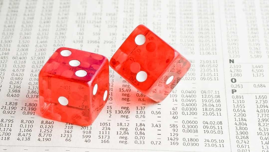 A pair of red dice sit on top of a printout with financial values on it