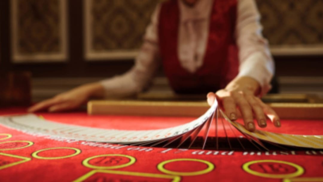 Croupier shuffling cards on a red felt table