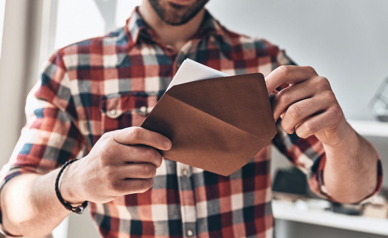 A man opens an envelope with a dinner party invitation.