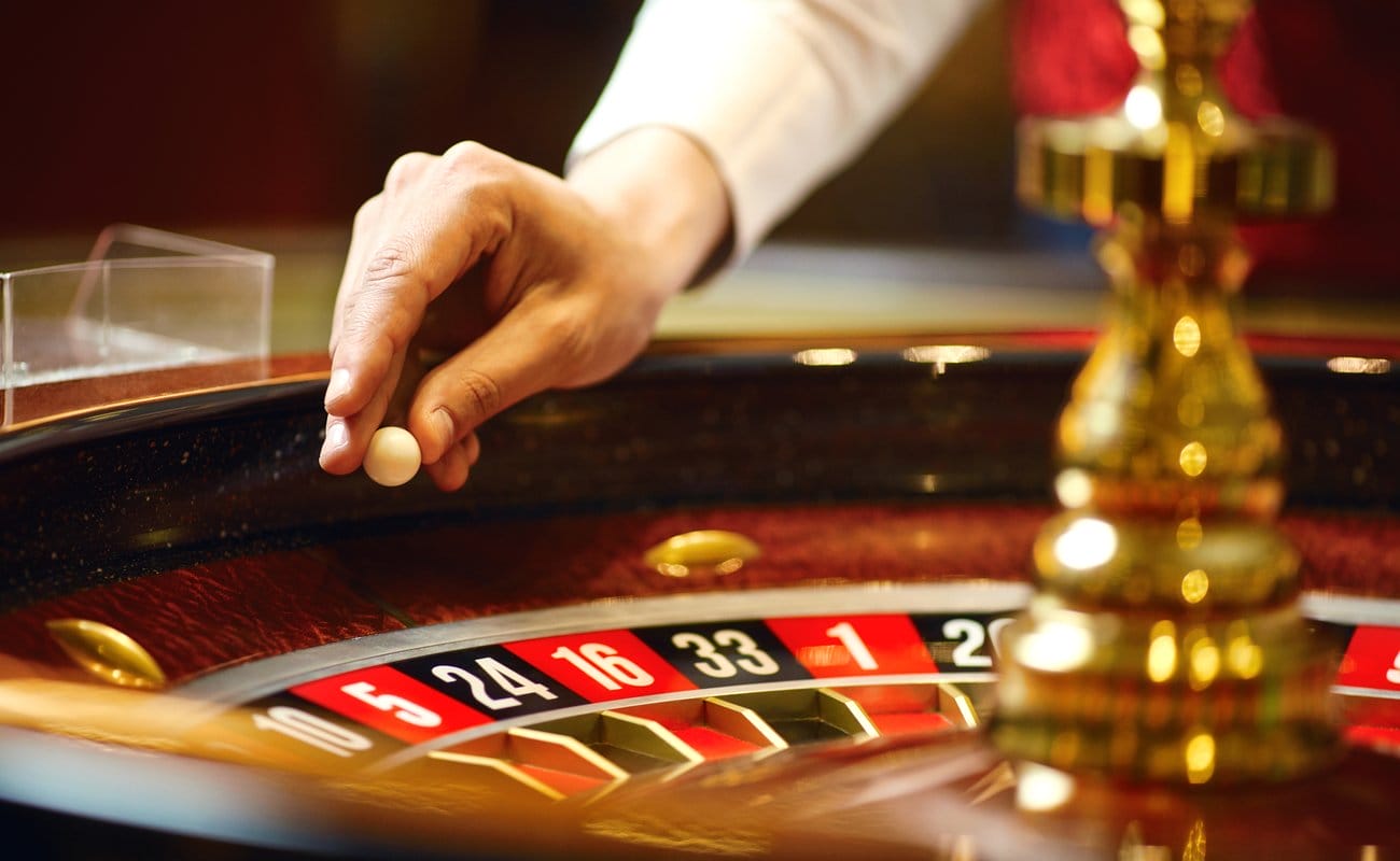 Close-up of a casino dealer about to place a ball on a roulette wheel.