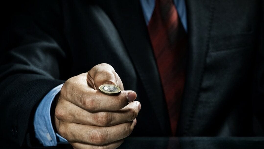 Close-up of a businessman about to toss a coin.