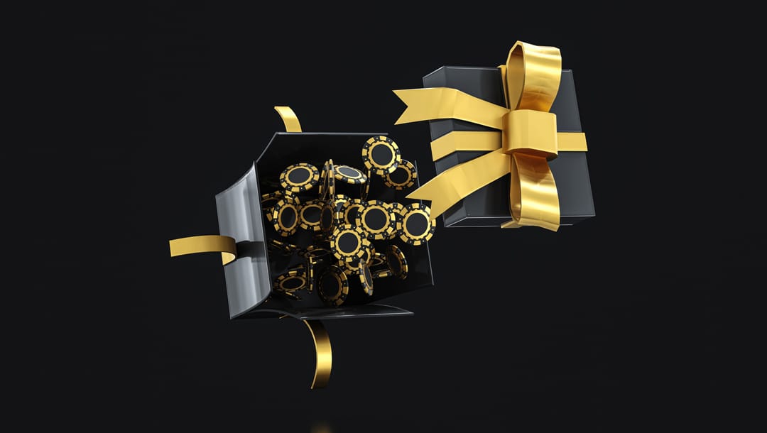 Black and gold casino chips bursting out of a black gift box with gold ribbon against a black background.