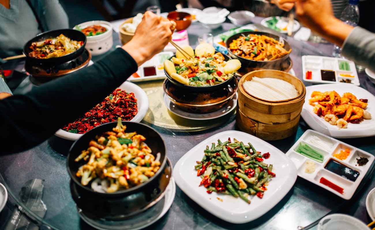 A group of people sharing a variety of Chinese dishes.