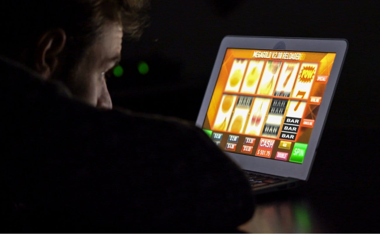 A man plays online slots on a laptop at night.