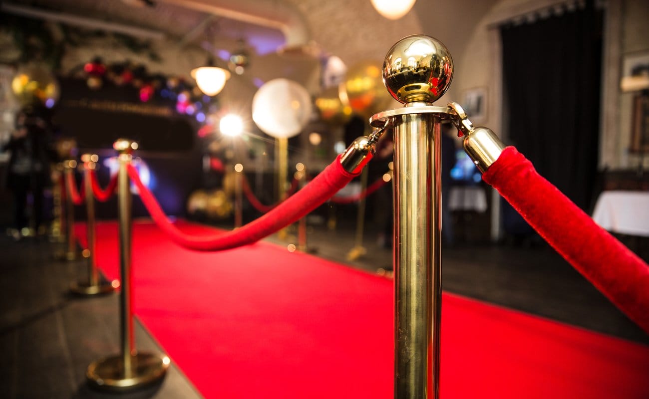 A red carpet and gold stanchions at a celebrity event.