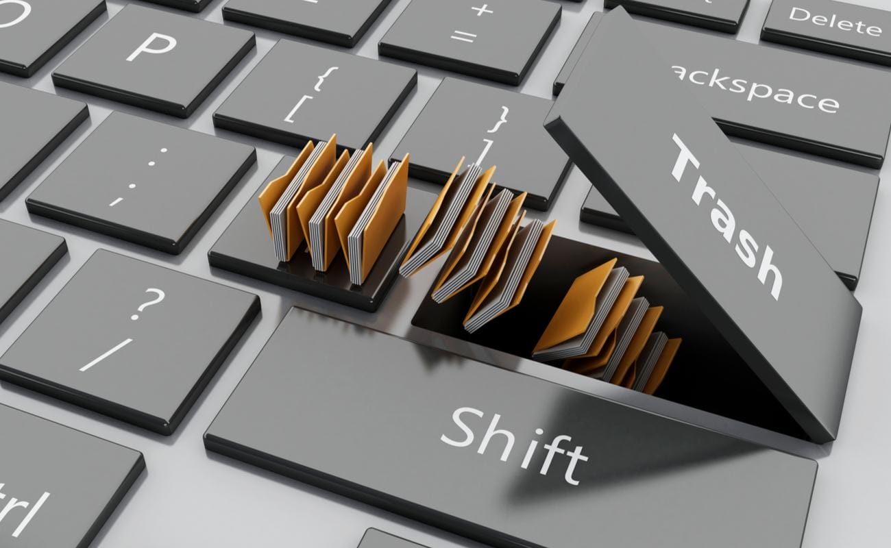 A 3D-rendered illustration of computer files disappearing into a keyboard under the Trash key.