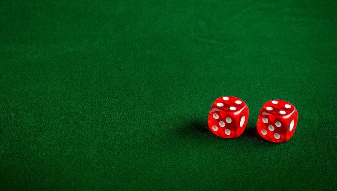 Two red and white dice on a green felt table.