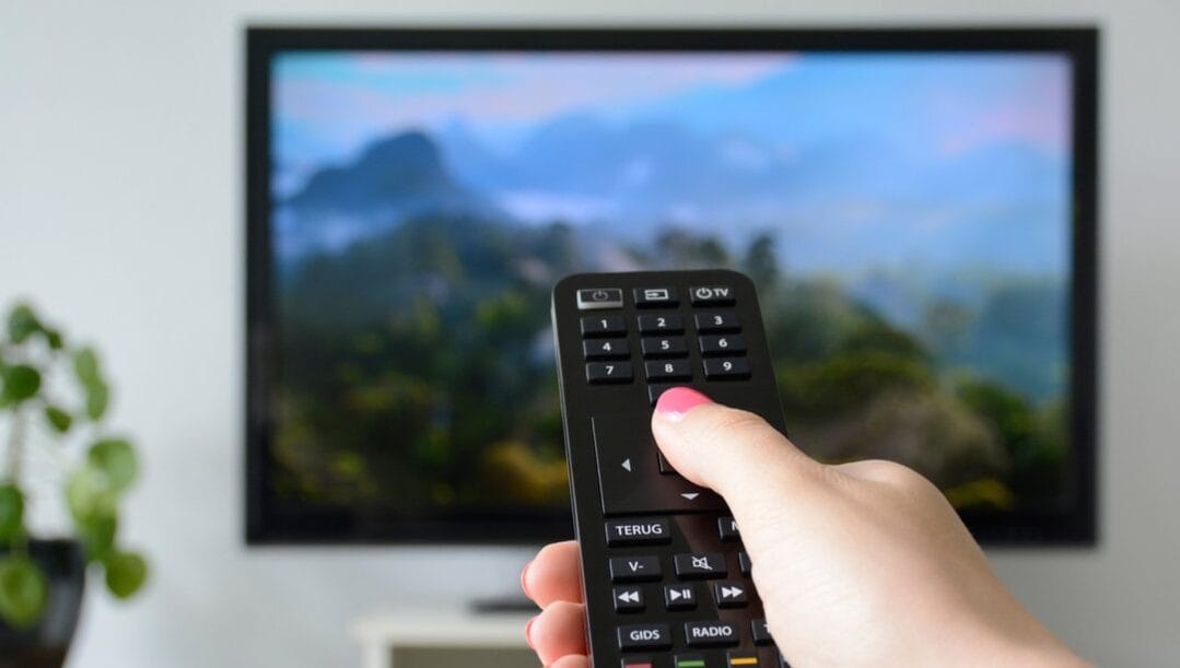 A woman using her TV remote to change channels.