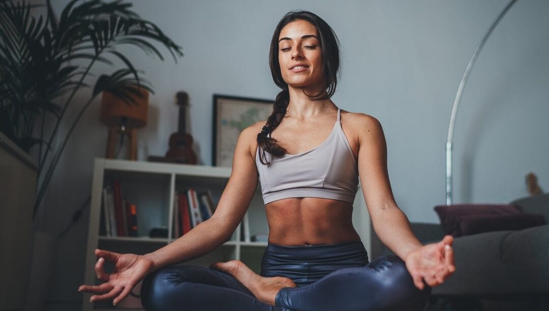 A woman sitting in half lotus pose, meditating.