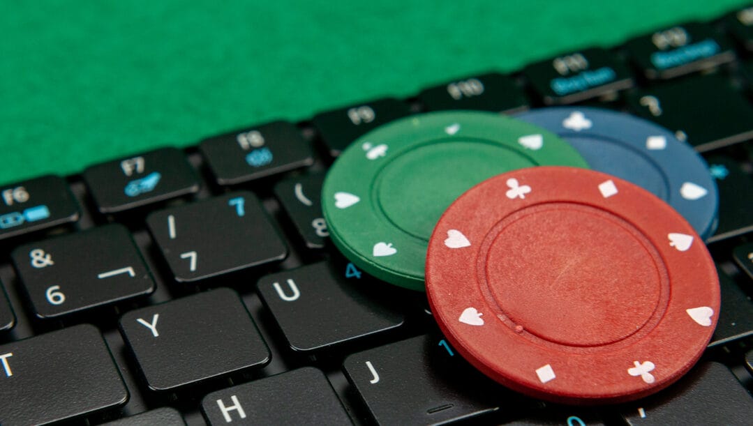 Green, red and blue poker chips on top of a keyboard.