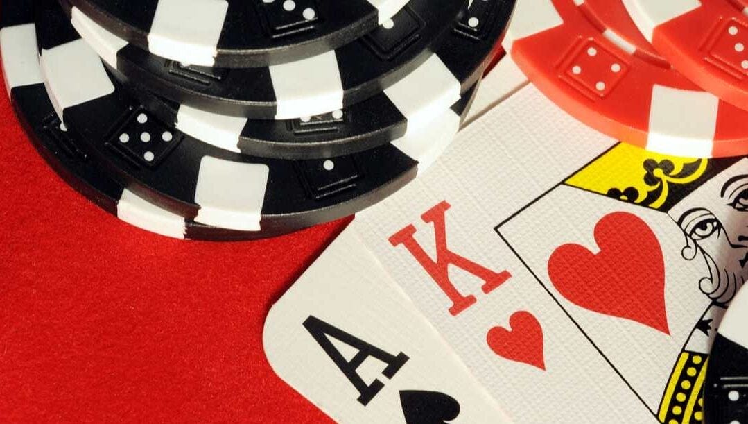 Playing cards showing a ‘blackjack’ with casino chips on a red felt table.
