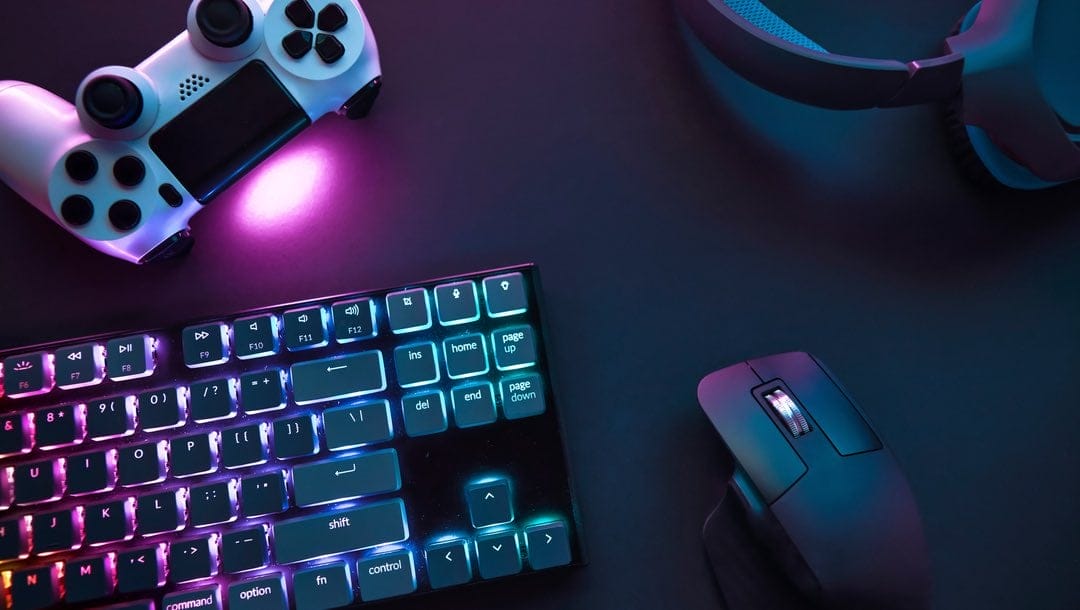 Top-down view of various gaming accessories, colorfully illuminated, laying on a table.