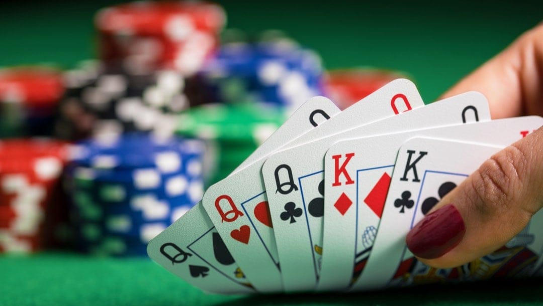 Closeup of poker cards with chips in the background.