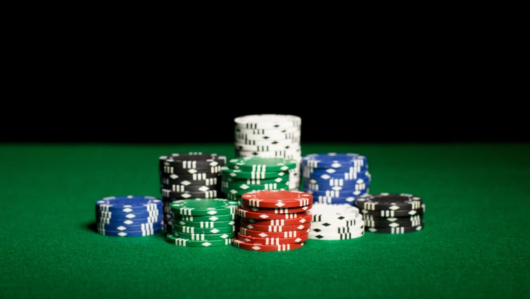 Stacks of various colored poker chips on a green felt casino table.