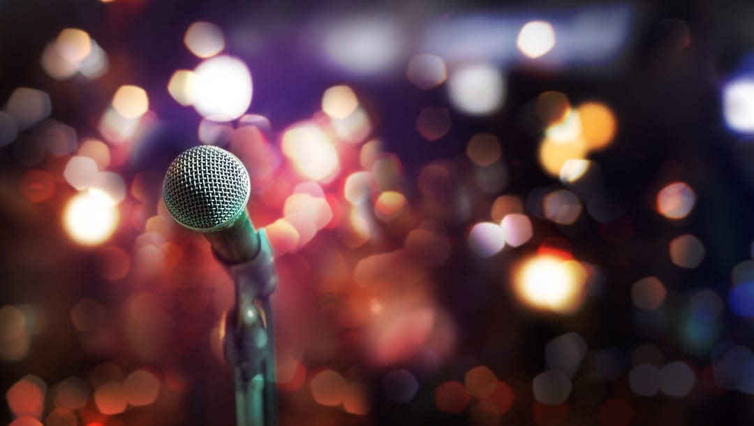 Close up of microphone in a concert hall with blurred lights in the background.