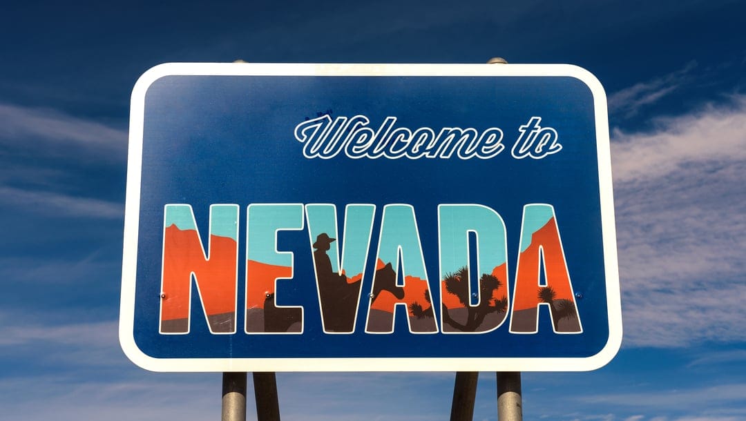 A ‘Welcome to Nevada’ sign against a blue sky.