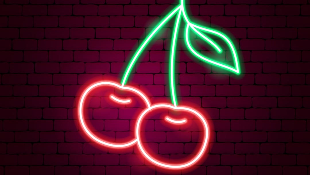 A neon cherry sign on a wall.