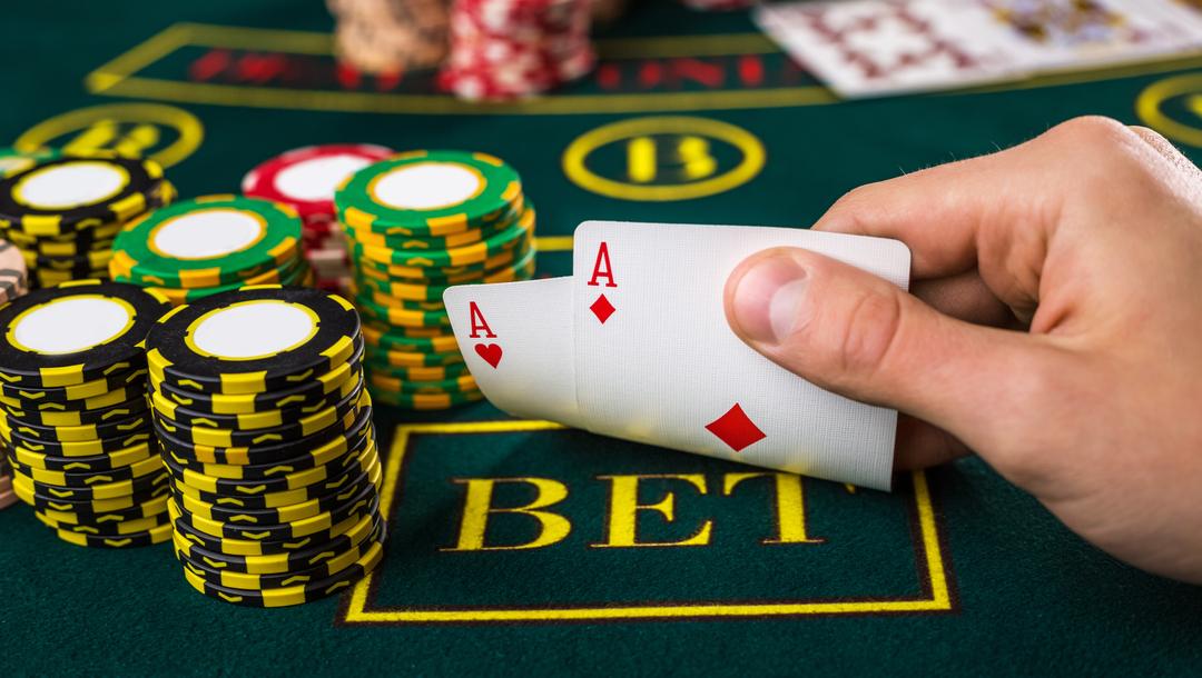 A poker player checks their hole cards and sees two aces.