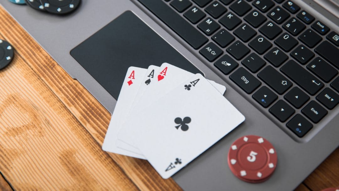 Four Aces and some poker chips on a laptop.