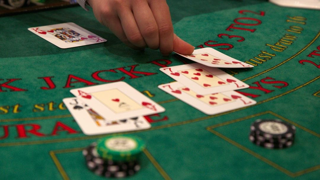 A dealer placing a card down on a blackjack table.