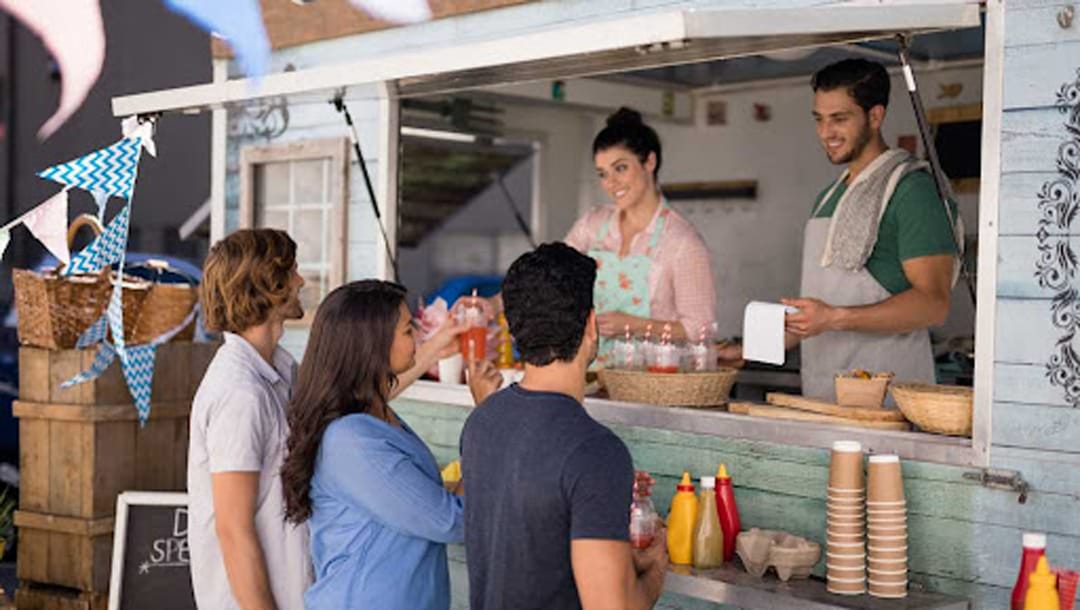 A man and woman being served at a food truck.