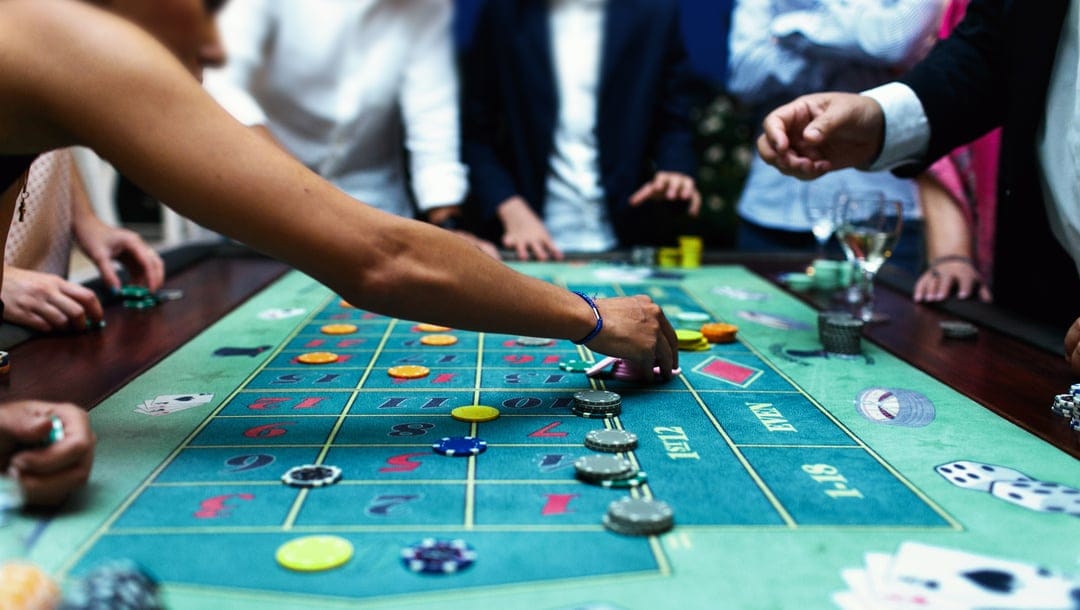 Gamblers standing around a casino table.