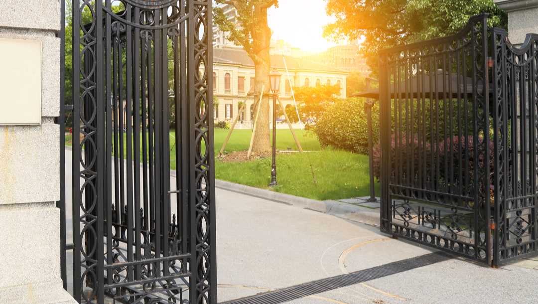 Open wrought iron gates leading to a mansion.