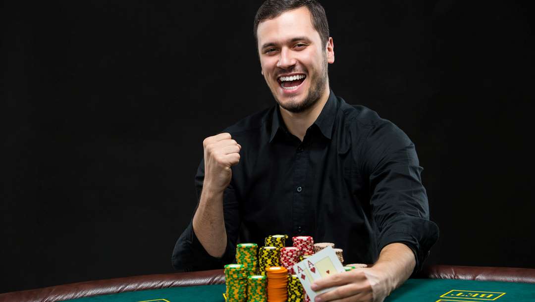 A smiling poker player reveals a pair of aces.