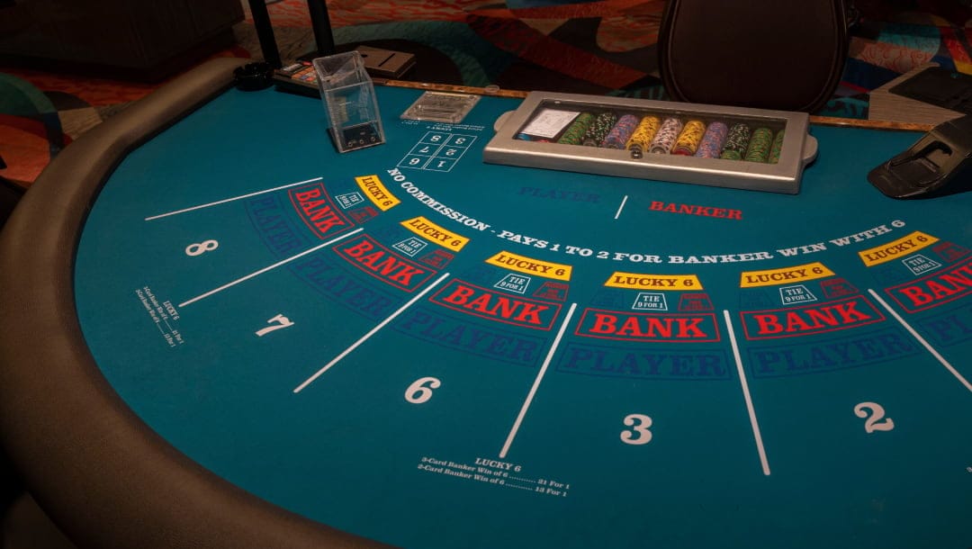 A view of an empty green baccarat casino table with brown leather edging. The table has positions for eight betters that are numbered one to eight, with the betting options for the bank and player. At the back of the table are the discard box, the casino chip rack, and the card shoe.
