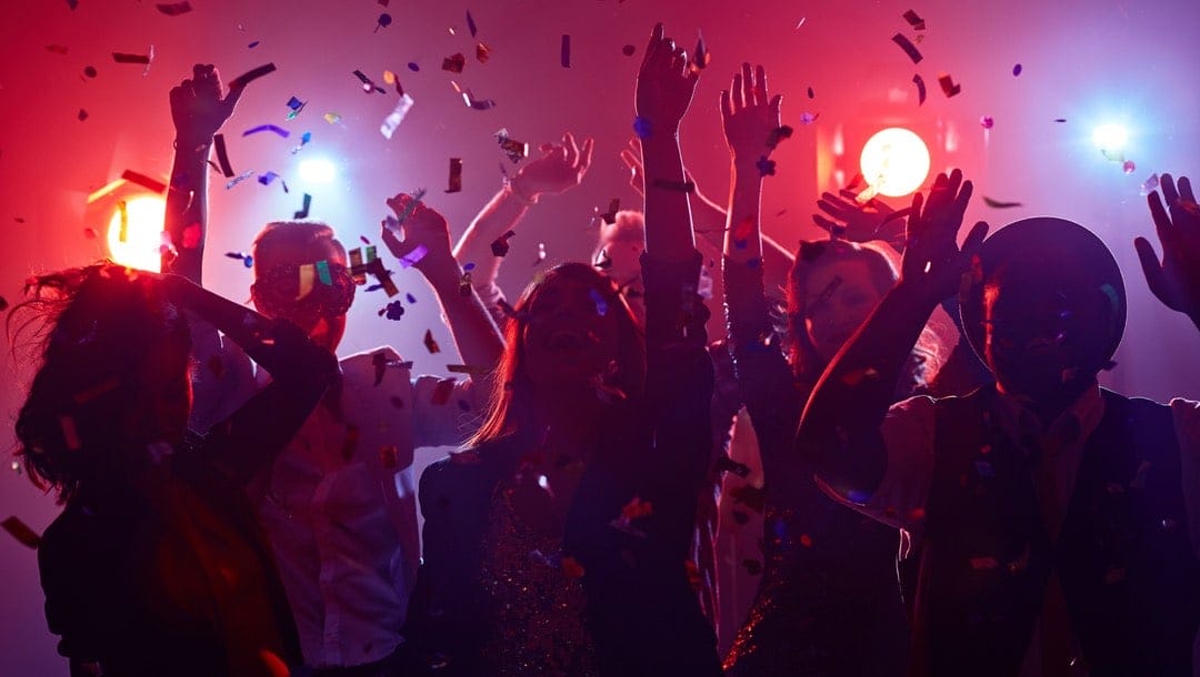 People dancing under neon lights in a nightclub.
