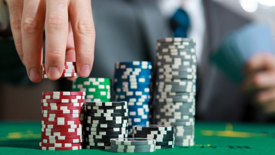 A player grabs a few casino chips from his stack.